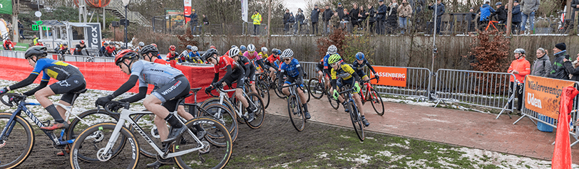 Wielrenvereniging fietsen in groep van betegelt parcours naar gras parcours - NK Veldrijden 2026